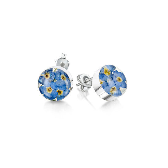 The image shows a pair of sterling silver earrings with stud fastenings, the earrings are round and contain real forget-me-not flowers. contained within resin and mounted in sterling silver.