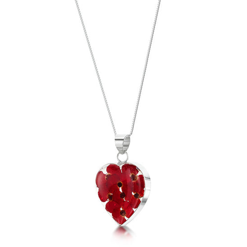 The image shows a heart-shaped sterling silver pendant. The pendant contains real poppy flowers in a clear resin mounted within sterling silver on an 18 inch chain.
